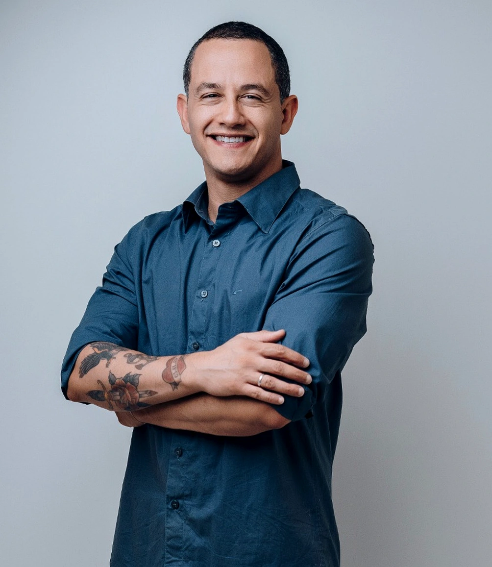 Teacher Petta sorrindo, de braços cruzados